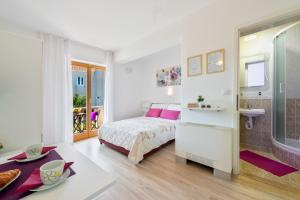 a white bedroom with a bed and a bathroom at Cina Apartments in Cavtat