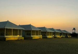 a row of tents in the desert at sunset at Sam Sand Dunes Jaisalmer in Jaisalmer