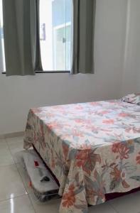 1 cama en una habitación con una sábana estampada de flores en Jacuipe Sun House, en Camaçari
