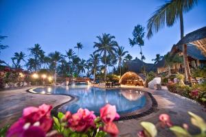 una piscina en un complejo con palmeras y flores rosas en Jaz Amaluna Hotel, en Uroa