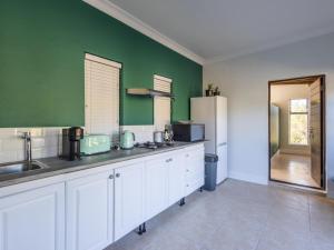 a kitchen with white cabinets and a green wall at Cliffside Suites in Plettenberg Bay