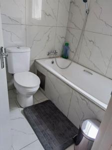 a white bathroom with a toilet and a bath tub at Beautiful apartment behind Illanga Mall in Mataffin