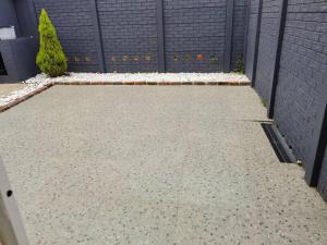 a garden with a retaining wall and a driveway at Beautiful apartment behind Illanga Mall in Mataffin