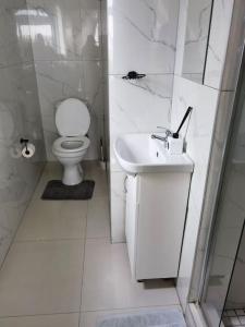 a white bathroom with a toilet and a sink at Beautiful apartment behind Illanga Mall in Mataffin