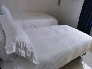 Cama blanca con sábanas y almohadas blancas en Beautiful apartment behind Illanga Mall en Mataffin