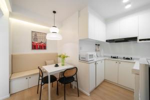 a kitchen with white cabinets and a table and chairs at Shanghai Downtown Yidu Apartment - 150m walk from Exit 5 of Jiashan Road Metro Station in Shanghai