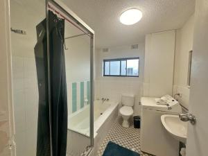 a bathroom with a tub and a toilet and a sink at Surfers Private Apartments in Gold Coast