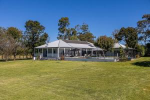 una casa con un gran campo de hierba delante de ella en 'Bonnie View' A Magnificently Luxurious Retreat, en Mudgee