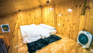 Habitación pequeña con cama en una pared de madera. en Dớt's Garden Homestay, en Da Lat