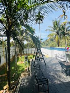 a resort with a pool and palm trees at Leisure familyvillas in Padinjarathara