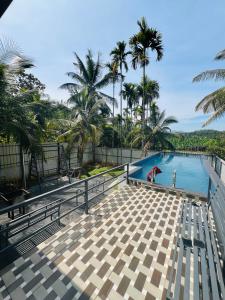 a swimming pool with palm trees in the background at Leisure familyvillas in Padinjarathara