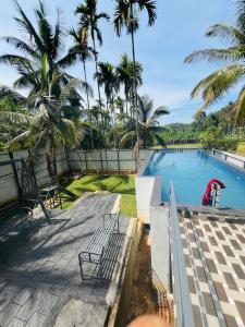 Blick auf einen Pool mit Palmen in der Unterkunft Leisure familyvillas in Padinjarathara
