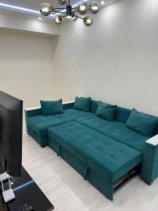 a blue couch in a living room with a tv at Cozy apartment - City Central in Tashkent