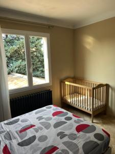 ein Schlafzimmer mit einem Kinderbett und einem großen Fenster in der Unterkunft La villa castellas in Carpentras + 23 Fotos