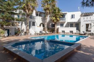 a swimming pool in front of a building with palm trees at Ampelos Prokopios in Agios Prokopios