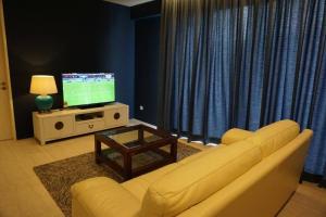 a living room with a couch and a television at Ferringhi Luxury Suite @ By The Sea in Batu Ferringhi