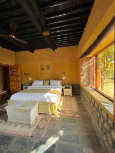 a bedroom with two beds and a large window at Prakriti Aalay - Riverside Mountain View Boutique Eco Resort in Dharamshala