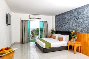 Langkapuri Resort Langkawi في بانتايْ سينانج: غرفه فندقيه بسرير وشرفه