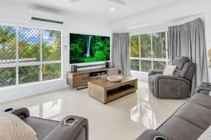 a living room with a tv and a couch and chairs at Mount Sheridan home with Breath taking views in Cairns