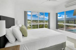 a white bedroom with a large bed and two windows at Mount Sheridan home with Breath taking views in Cairns