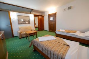 a hotel room with two beds and a chair at Hotel Zámok Topoľčianky in Topoľčianky