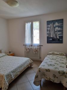 a bedroom with two beds and a window with a sailboat at Giacomo Home in Marina di Cecina