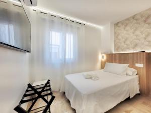 una camera da letto bianca con un letto e una televisione di The Stylish Apartment a Puerto de la Cruz