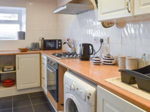 a kitchen with a washing machine and a sink at Bron Haul, Mountain Views in Brynteg