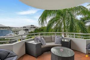 uma varanda com um sofá e cadeiras e uma palmeira em The heart of Cairns City with panoramic views em Cairns
