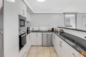 uma grande cozinha com armários e electrodomésticos brancos em The heart of Cairns City with panoramic views em Cairns
