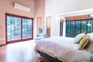 Schlafzimmer mit einem Bett, einem Stuhl und Fenstern in der Unterkunft Airbnb at Bailyes in Pretoria