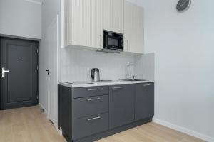 a kitchen with a sink and a microwave at Stylish Grey Apartments with a City View in Poznań by Renters in Poznań