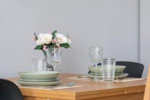 een tafel met borden en glazen en een vaas met bloemen bij Stylish Grey Apartments with a City View in Poznań by Renters in Poznań