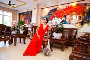 Lotus Garden Muine Resort & Spa في موي ني: امرأة ترتدي ثوب احمر تقف في غرفة