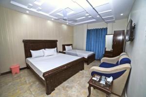 ein Schlafzimmer mit einem Bett, einem Sofa und einem Stuhl in der Unterkunft Royal Blue inn Hotel in Islamabad