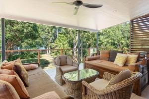 a screened in porch with a couch and chairs at Bramston Beach - Premium Holiday House in Bramston Beach