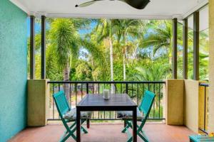 een tafel en stoelen op een balkon met palmbomen bij Port Douglas Vacation Holiday Unit in Port Douglas