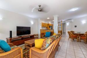 un soggiorno con divano e TV a schermo piatto di Yasmin at Coral Horizons: Retro Vibes on the Beach a Palm Cove