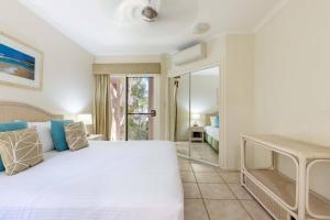 una camera da letto con un grande letto bianco e una porta di Yasmin at Coral Horizons: Retro Vibes on the Beach a Palm Cove Altre 17 foto