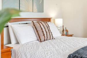 una cama con almohadas blancas encima en Edge Hill - spectacular views of the city and sea en Edge Hill
