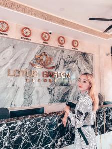 a woman is standing in front of a sign at Lotus Garden Muine Resort & Spa in Mui Ne