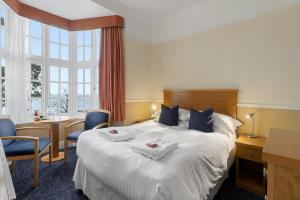 a hotel room with a bed with towels on it at Babbacombe Royal Hotel and Carvery in Torquay