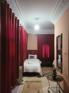 um quarto com cortinas cor-de-rosa e uma cama com uma mesa em Chambre d'hôtes aya em Ouzoud