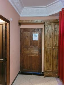 Cette chambre dispose de deux portes en bois et d'un rideau rouge. dans l'établissement Chambre d'hôtes aya, à Ouzoud