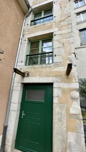 una puerta verde en un edificio con dos ventanas en Appartement au calme dans le quartier historique pour 4 personnes avec espace extérieur, en Pau