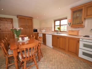 a kitchen with a wooden table and a table and chairs at 2 Bed in Bradworthy KANNA in Bradworthy