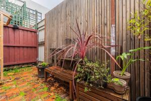 una valla de madera con un banco y plantas en ella en Explore the Locale in a Sustainable Renovated Pub en Melbourne