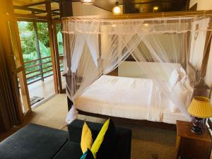 a bedroom with a canopy bed and a couch at Cozy Homestay in Ella
