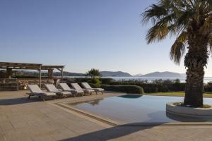 a group of lounge chairs and a palm tree next to a pool at Porto Heli - Heaven on Earth Villa in Ermioni