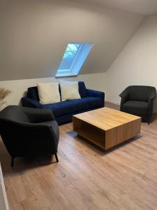 sala de estar con sofá azul y 2 sillas en Ferienwohnung Haus Peters "De Groote", en Marschkamp